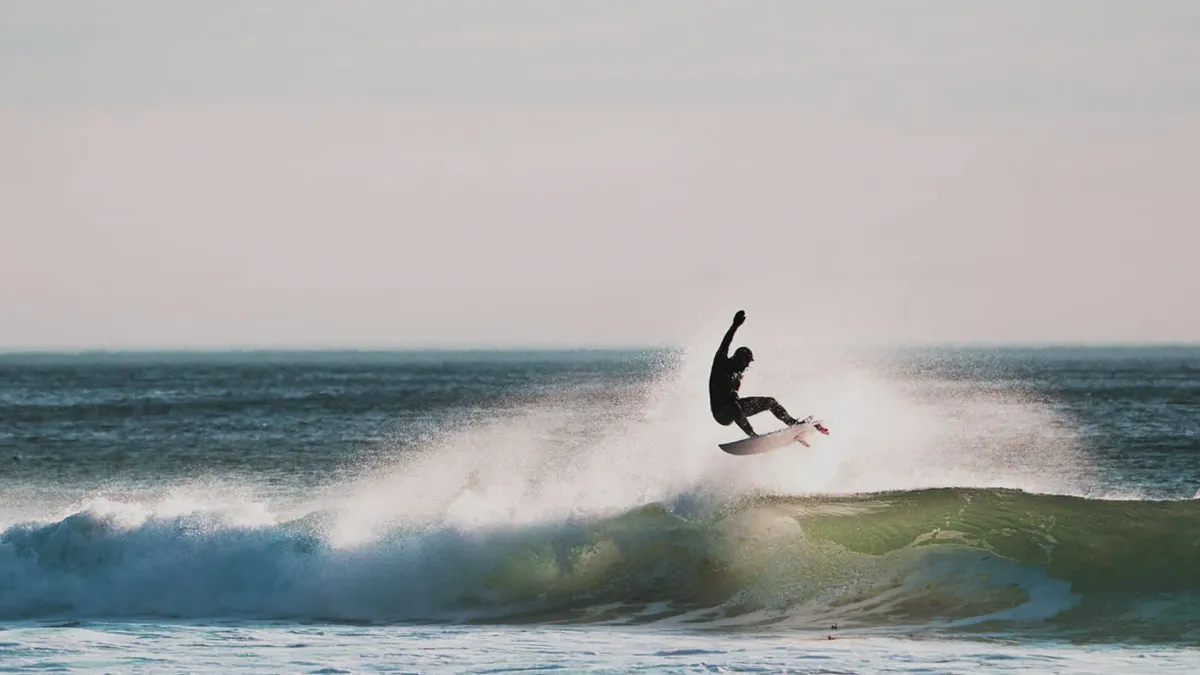 Surfer i luften over en bølge på Varangerhalvøya