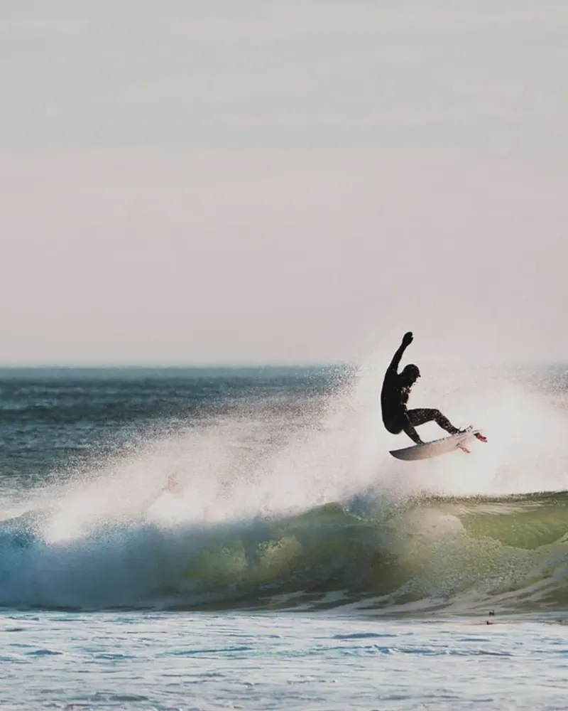 Surfer i luften over en bølge på Varangerhalvøya