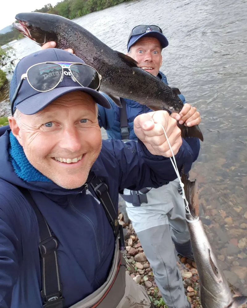 Two fly fishers showing off a large salmon caught in the river at Jakobselv