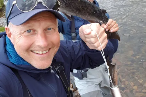 Two fly fishers showing off a large salmon caught in the river at Jakobselv