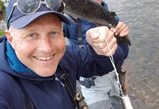 Two fly fishers showing off a large salmon caught in the river at Jakobselv