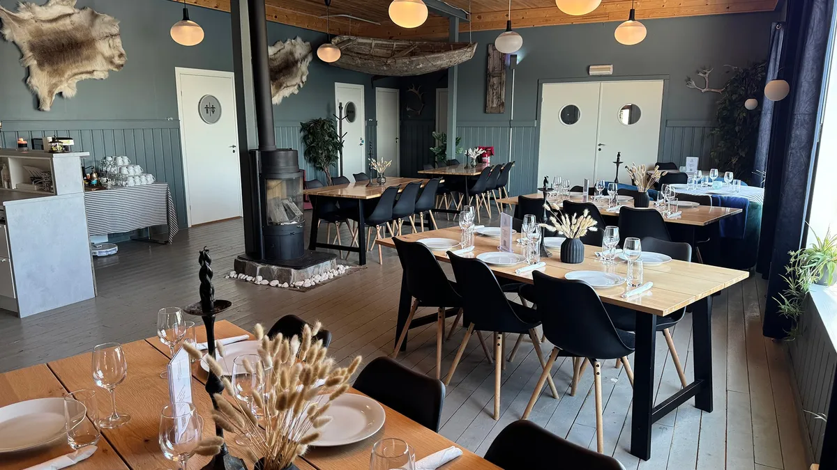 Dekkede bord i restauranten på Jakobselvkaia, med reinskinn og vedovn