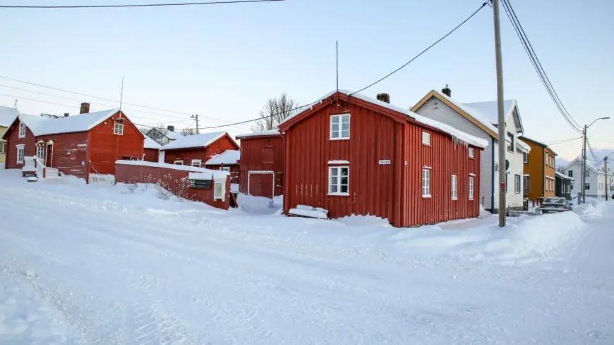 Red-painted log house at Tuomainengården seen from the street on a winter morning, with snow on the ground